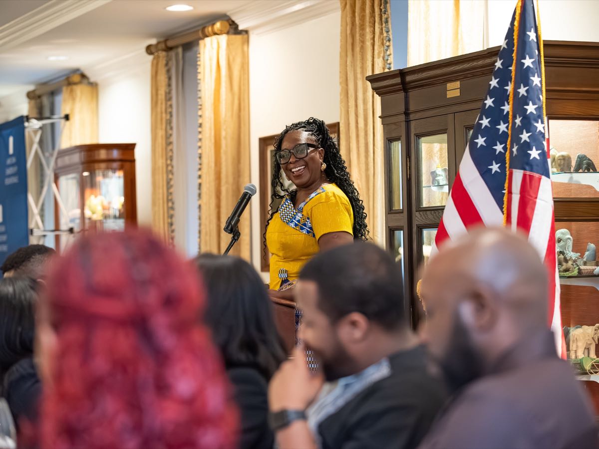 A speaker at the podium seen across the seated room